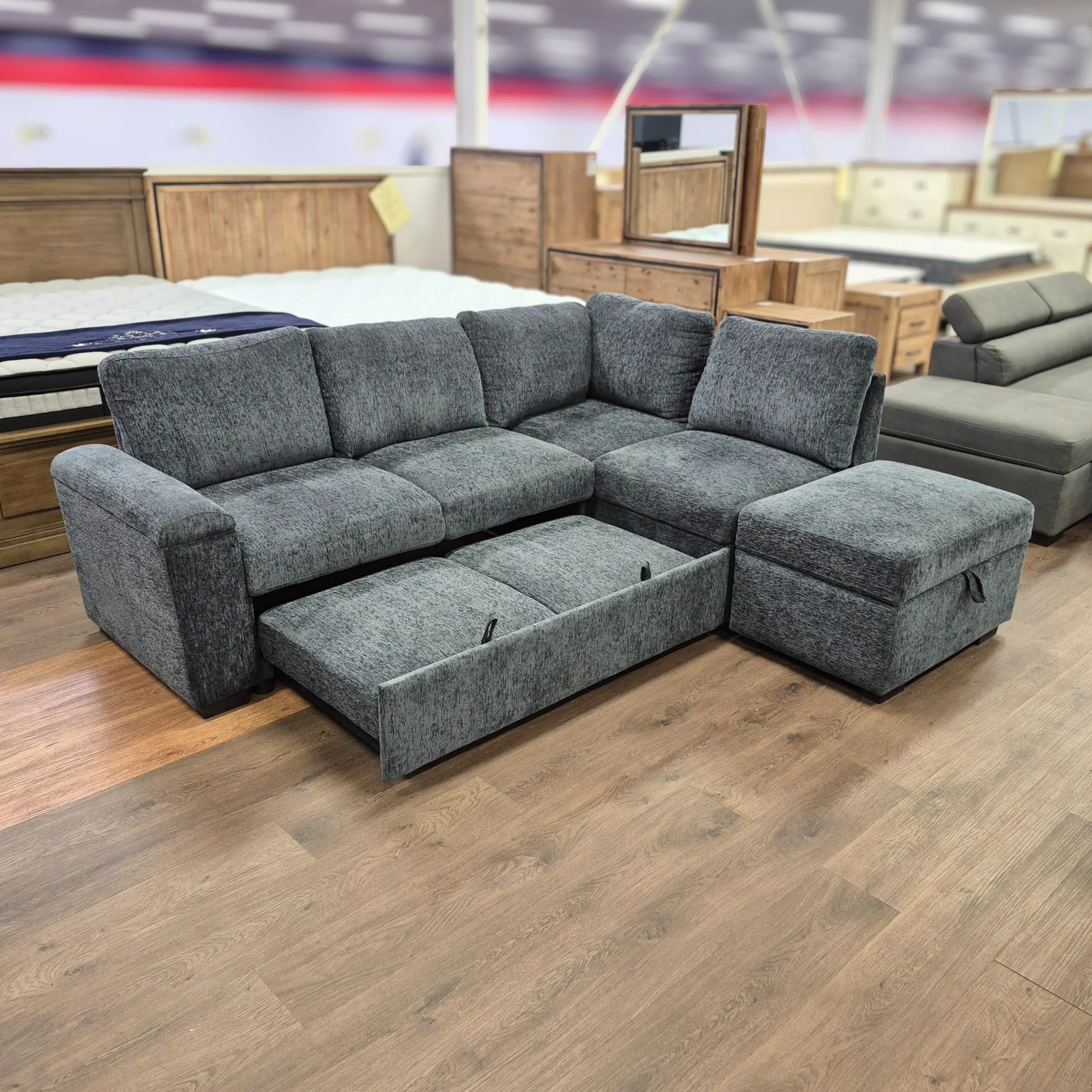 Grey sectional sofa with storage chaise and pull-out bed in furniture showroom