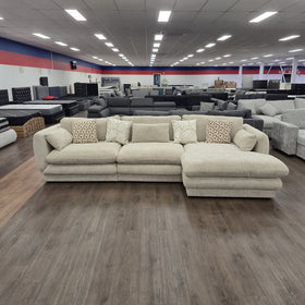Otway L-Shaped Fabric Lounge in Beige in the showroom, wide view showing the full length of the lounge and right-hand chaise.