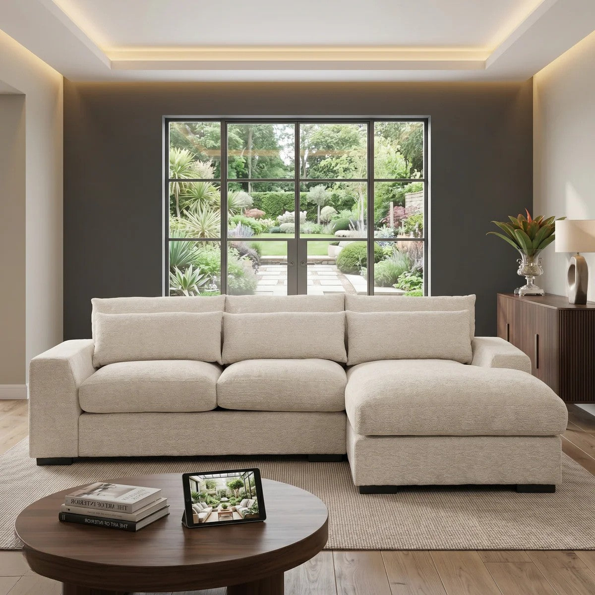 Oxford 3 Seater Couch with Chaise in a bright modern living room, featuring light beige upholstery and plush cushions with a large window view of a garden in the background.