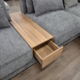 Close-up of the Oxley Modular Corner Lounge timber console module set between two seat modules, with its pull-out drawer open.