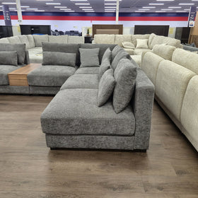 Oxley Modular Corner Lounge in Dark Grey viewed end-on from the chaise, showing seat depth, scatter cushions and the low timber base.