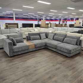Oxley Modular Corner Lounge in Dark Grey photographed front-on in the showroom, showing the full corner layout and deep seat cushions.