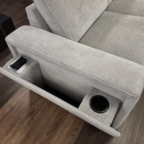 Close-up of the Pavillion L-shaped fabric sofa arm in silver, with the console folded down to show the power point and USB module, cup holder and open arm storage compartment