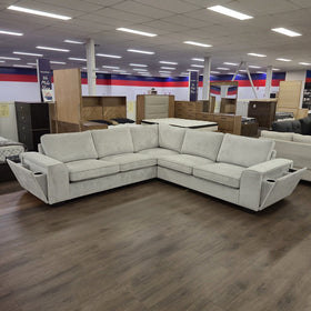 Pavillion L-shaped fabric sofa in silver with both arm consoles folded down showing the cup holders, on the floor of The A2Z Furniture showroom