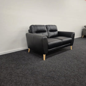 Pearl 2 Seater Leather Lounge in black leather, angled side view showing the rounded armrest, side profile and splayed timber legs, in The A2Z Furniture showroom