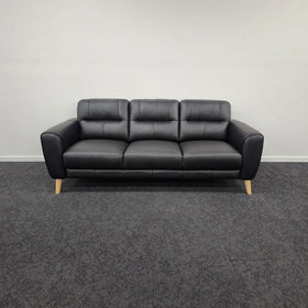 Pearl 3 Seater Leather Lounge in black leather, front view showing three seat cushions, split back cushions and pale timber tapered legs, on display in The A2Z Furniture showroom