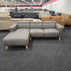 Penelope 3 Seater Leather Lounge with Chaise in Anthracite, front-on view with the right-hand chaise when sitting and the adjustable headrests raised, on display in The A2Z Furniture showroom.