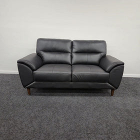 Penrith 2 Seater Leather Sofa in black, photographed front-on in The A2Z Furniture showroom, showing the two seat cushions, pillow-top backrests and tapered timber legs
