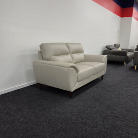 Penrith 2 Seater Leather Sofa in silver at a three-quarter angle in The A2Z Furniture showroom, showing the side profile and sloped padded armrest