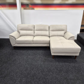 Modern light beige leather 3 seater sofa with chaise and wooden legs in showroom