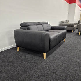 Percy 2 Seater Leather Lounge in black leather, rear three-quarter view showing the raised adjustable headrests, back panel and splayed timber legs, in The A2Z Furniture showroom