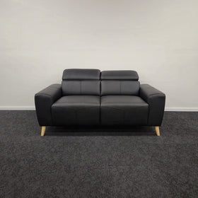 Percy 2 Seater Leather Lounge in black leather, front view with both adjustable headrests lifted upright, showing two seat cushions and splayed timber legs, in The A2Z Furniture showroom
