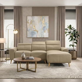 Percy 3 Seater Leather Lounge with Chaise in beige, featuring sleek wooden legs, placed in a modern living room with neutral tones, a round coffee table, artwork, and tall windows with curtains.