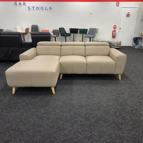 Percy 3 seater leather lounge with chaise in khaki, front-on view showing the chaise, wide arms and splayed timber legs, on the floor of The A2Z Furniture showroom