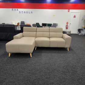 Percy 3 seater leather lounge with chaise in khaki, front-on with the adjustable headrests raised and the chaise on the right when sitting, in The A2Z Furniture showroom
