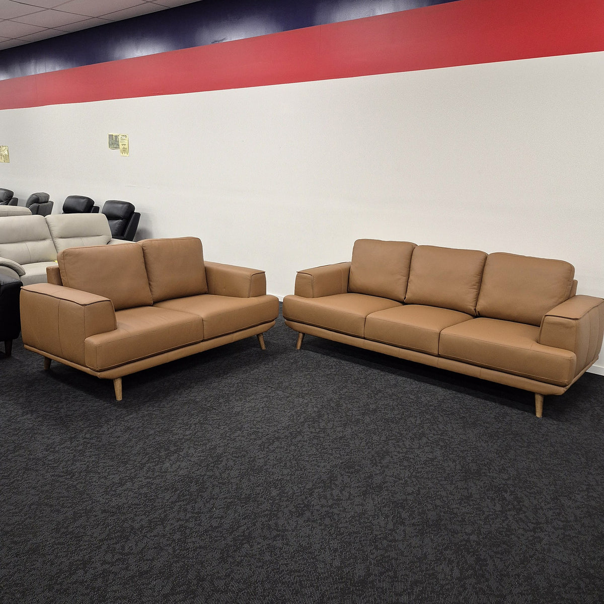 Picasso 3+2 Orange Leather Lounge Set on display in The A2Z Furniture showroom, showing the 2 seater and the 3 seater together in matching Orange leather with walnut-coloured wooden legs.