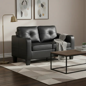 Modern living room with black leather sofa, wooden coffee table, and abstract art on the wall.