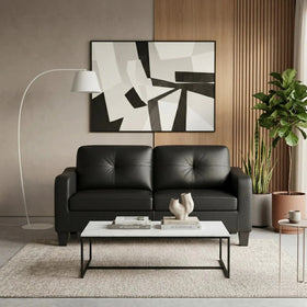 Modern living room with a black leather sofa, white coffee table, and abstract art on the wall.