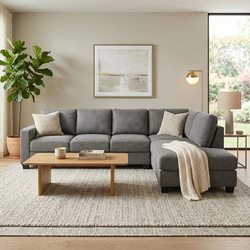 Gray sectional sofa in a living room with a coffee table, lamp, and artwork on the wall.