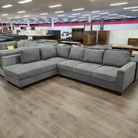 Modern grey corner sectional sofa in a furniture warehouse with wood flooring