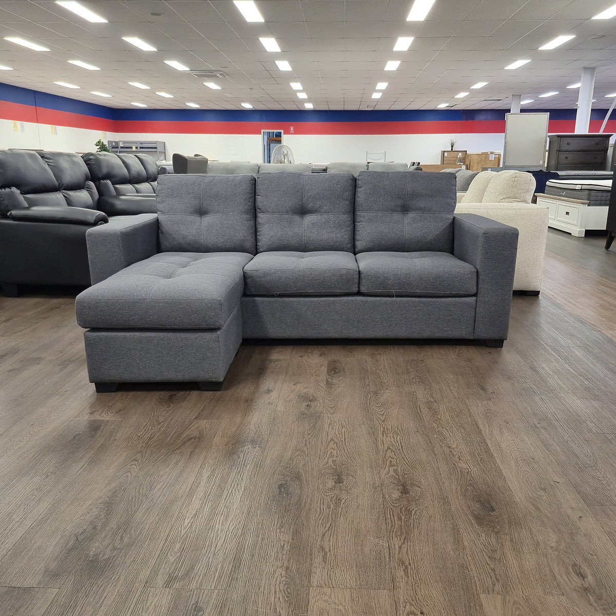 Sleek 3 Seater Chaise Lounge in dark grey fabric, front-on view with the reversible chaise fitted to the left, in The A2Z Furniture showroom