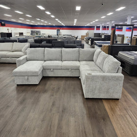 Springbrook Corner Sofa Bed in Grey on display in The A2Z Furniture showroom, showing the U-shaped layout with cup holders in both arms.