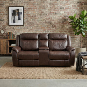 Sunshine 2 Seater Air Leather Electric Recliner Lounge in rich brown leather, placed in a cozy living room setting with a brick wall, wooden furniture, and indoor plant.