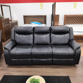Black leather three-seater recliner sofa in a showroom with wooden bedroom furniture