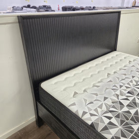 Detail view of the Tennyson Bed Frame's black wood base and upholstered mattress corner in The A2Z Furniture showroom.