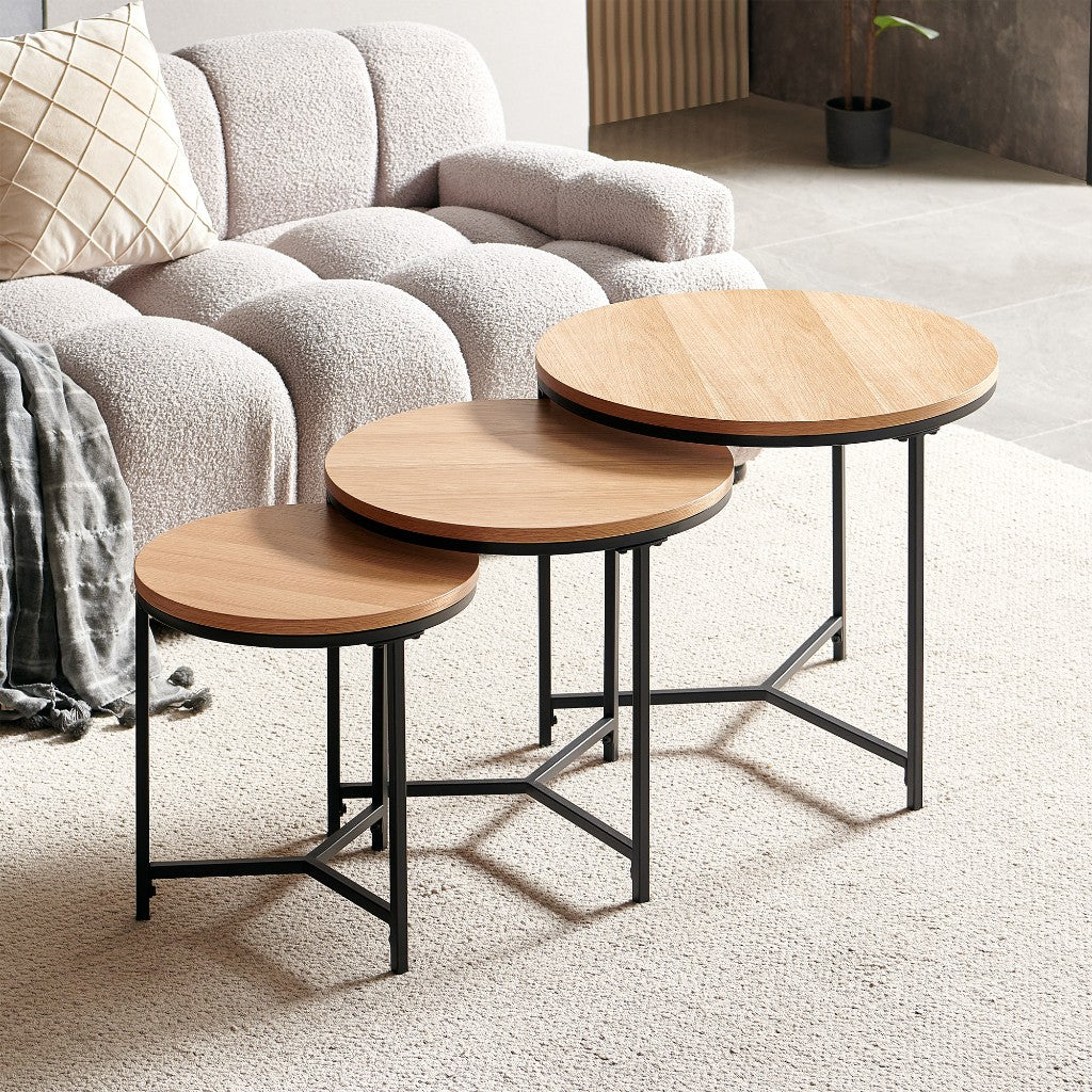 Ledora 3 piece round nesting coffee table set with oak-finish tops and black metal legs beside a sofa