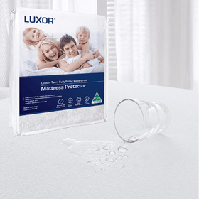 Waterproof mattress protector with spilled water demonstrating liquid resistance on bed.